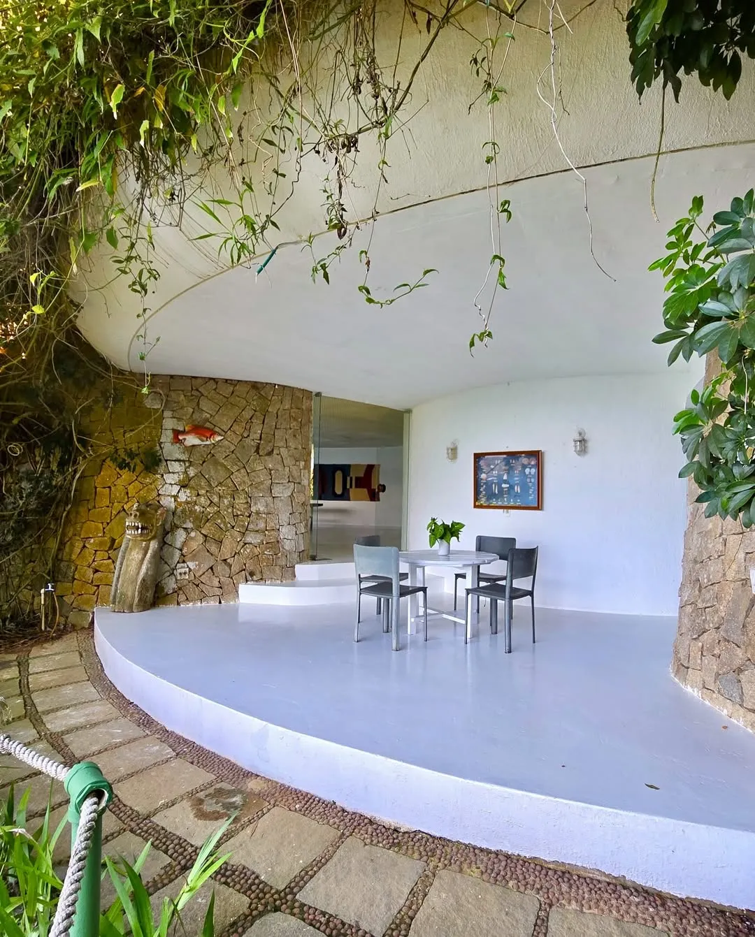 Pátio com mesa e cadeiras cercado por parede de pedra