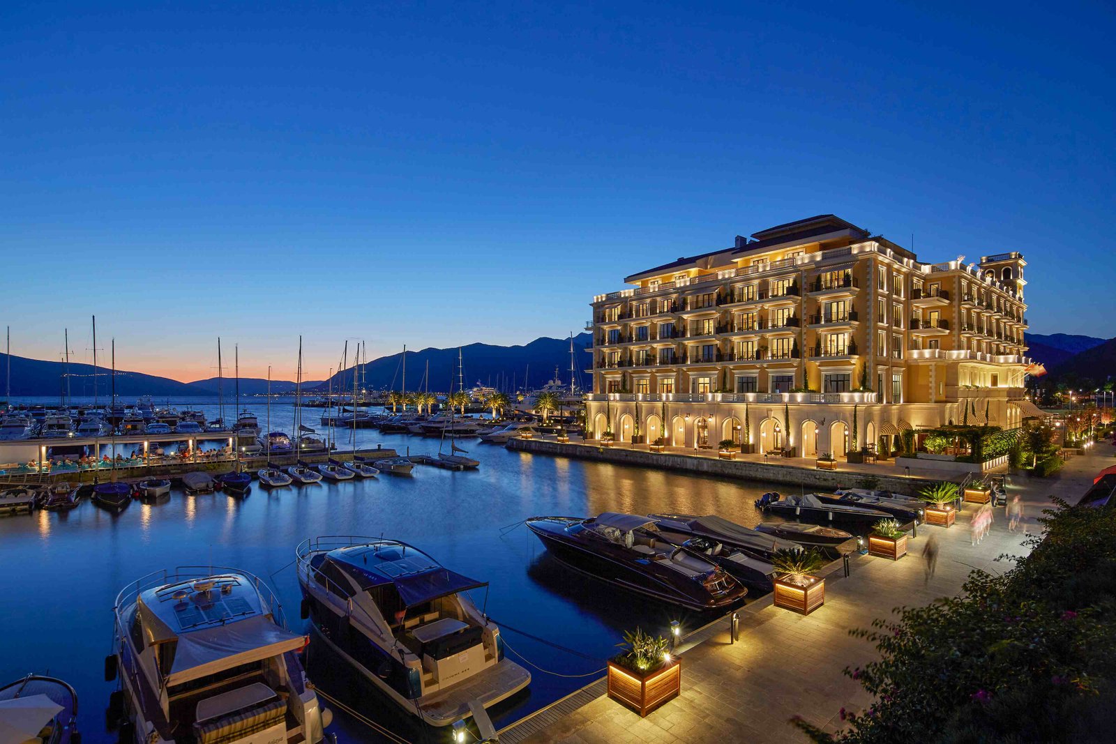 Fachada iluminada do hotel Regent Porto Montenegro à noite, junto à marina