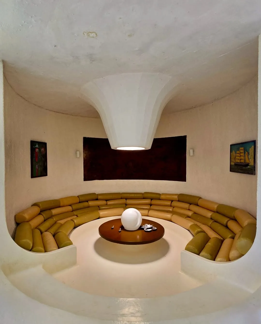 Sala de estar circular com sofás e vista para obras de arte