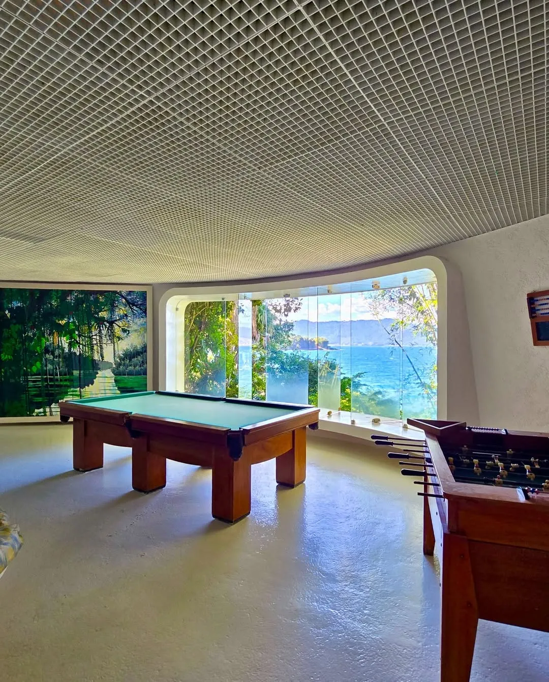 Sala de jogos com mesa de bilhar e vista para o mar