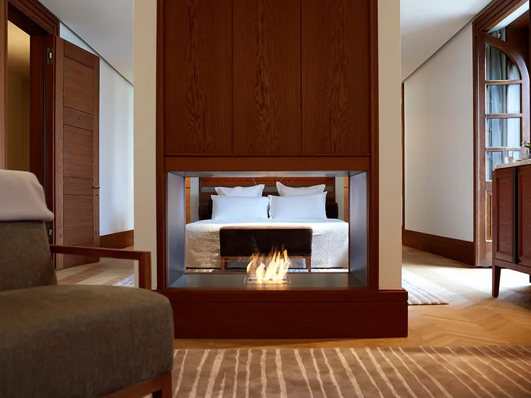 Quarto de luxo com paredes de madeira escura, cama king e lareira