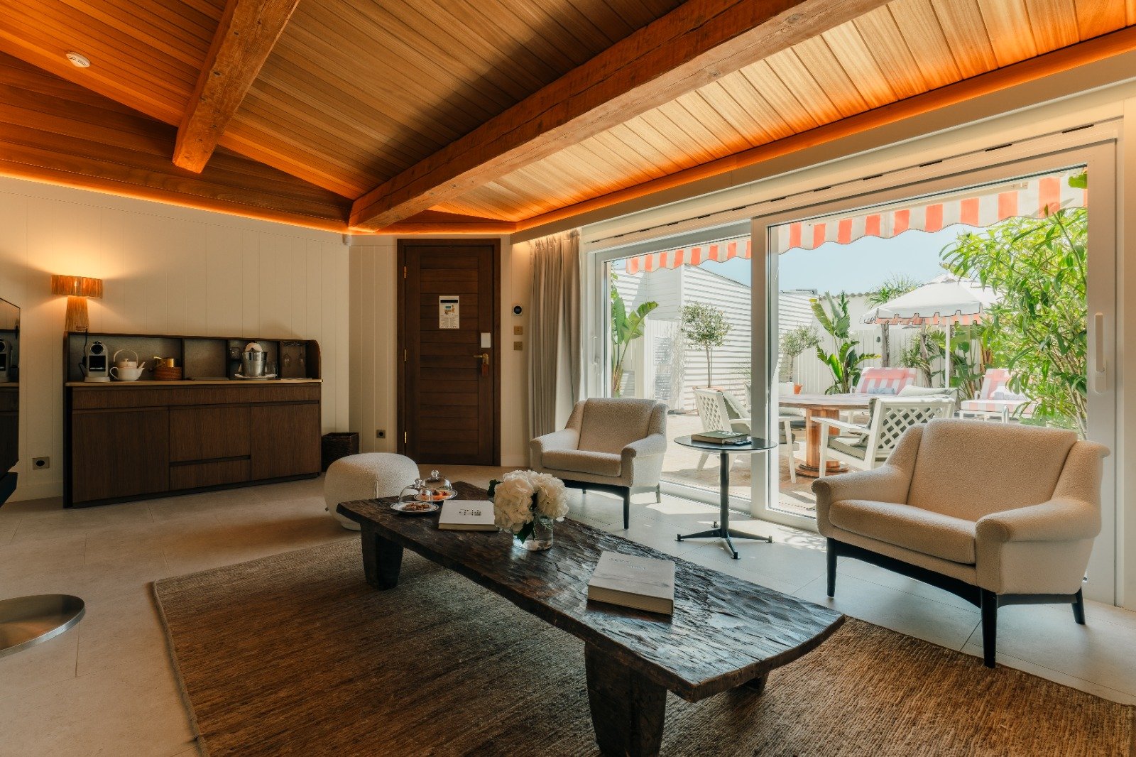 Sala de um dos nove bungalows do Épi 1959, com teto em madeira aparente e abertura para o terraço privativo