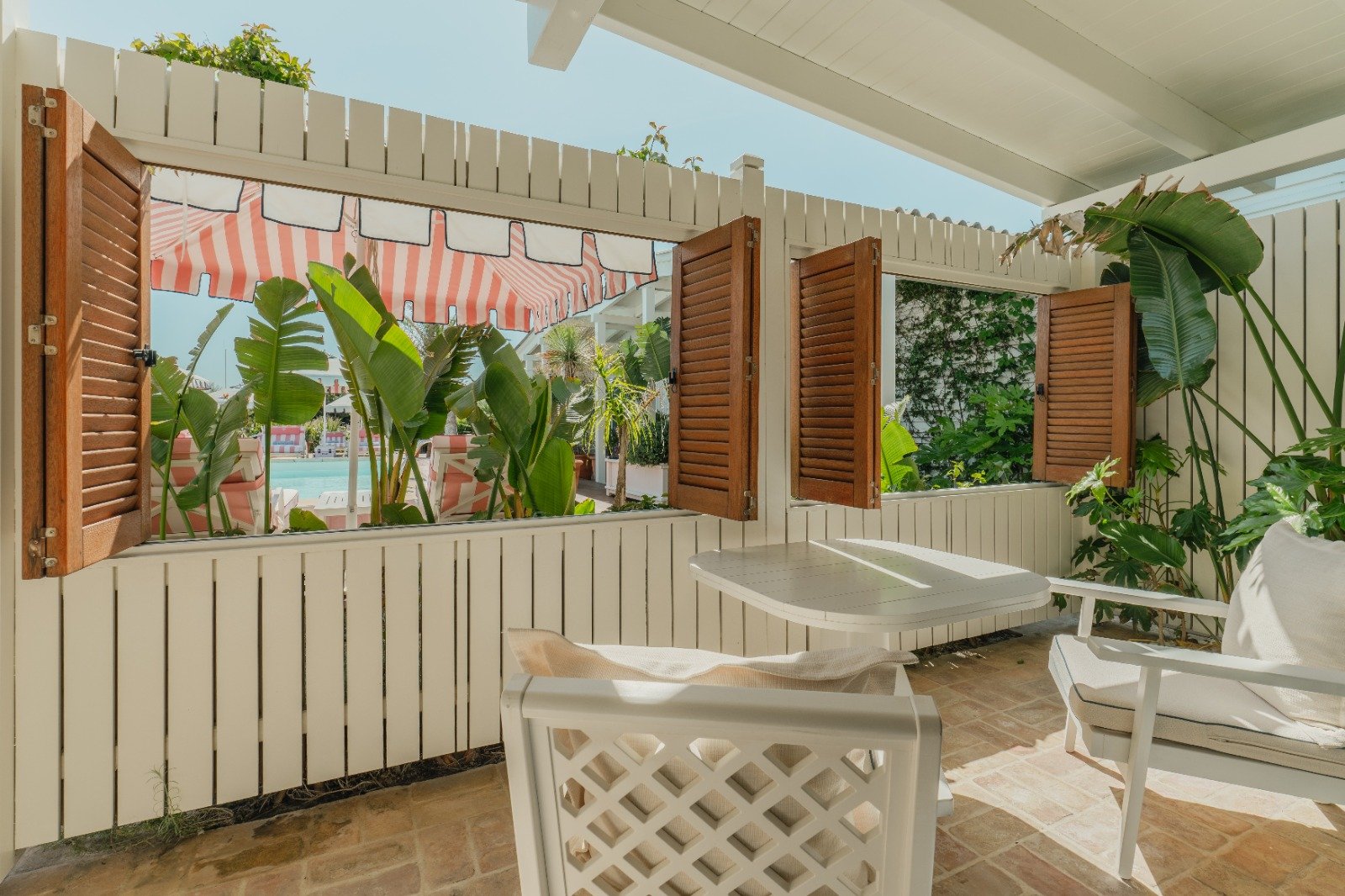 Terraço de bungalow do Épi 1959, com venezianas de madeira e vegetação, na Baía de Pampelonne