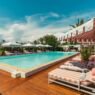 Piscina de 21 metros do Épi 1959 com deck de madeira, espreguiçadeiras listradas e guarda-sóis, na Baía de Pampelonne