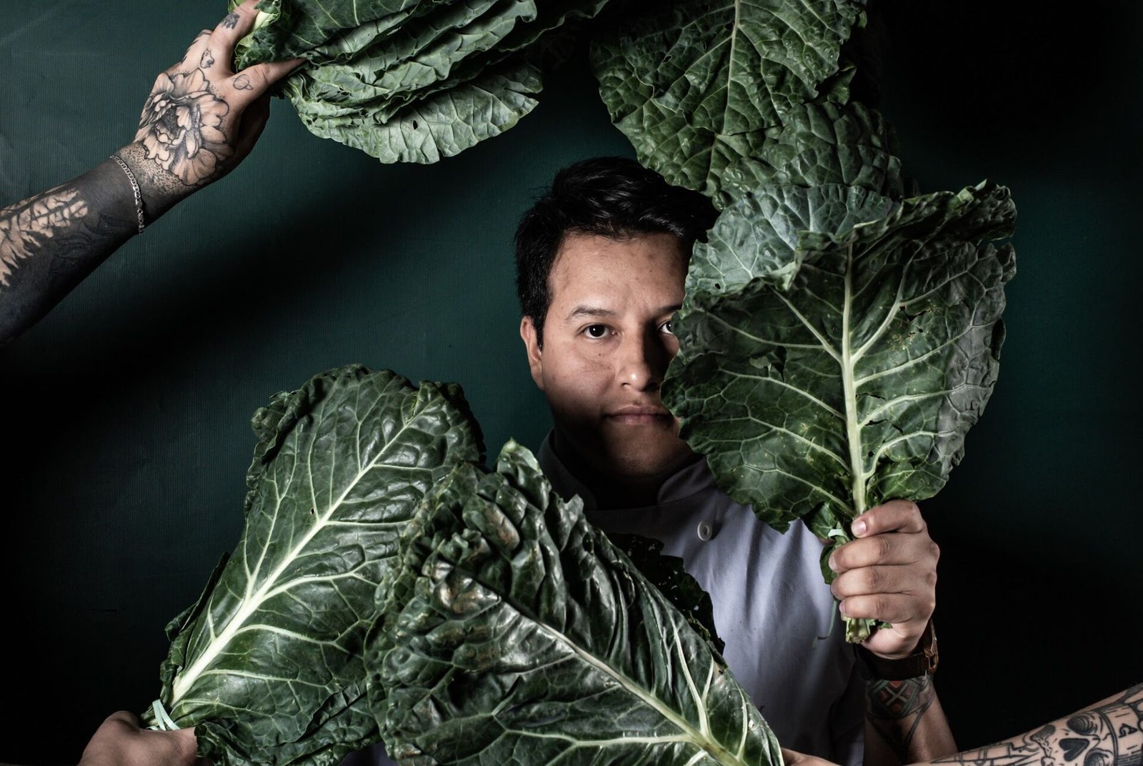 Chef Enrique Paredes em retrato de estúdio, entre folhas verdes