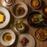 Pratos do Menu Experiência AMA.ZO dispostos sobre mesa de madeira, vistos de cima