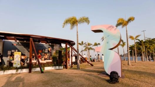 Área externa da ArtRio 2026 na Marina da Glória, com escultura de grande porte, palmeiras imperiais e a Baía de Guanabara ao fundo