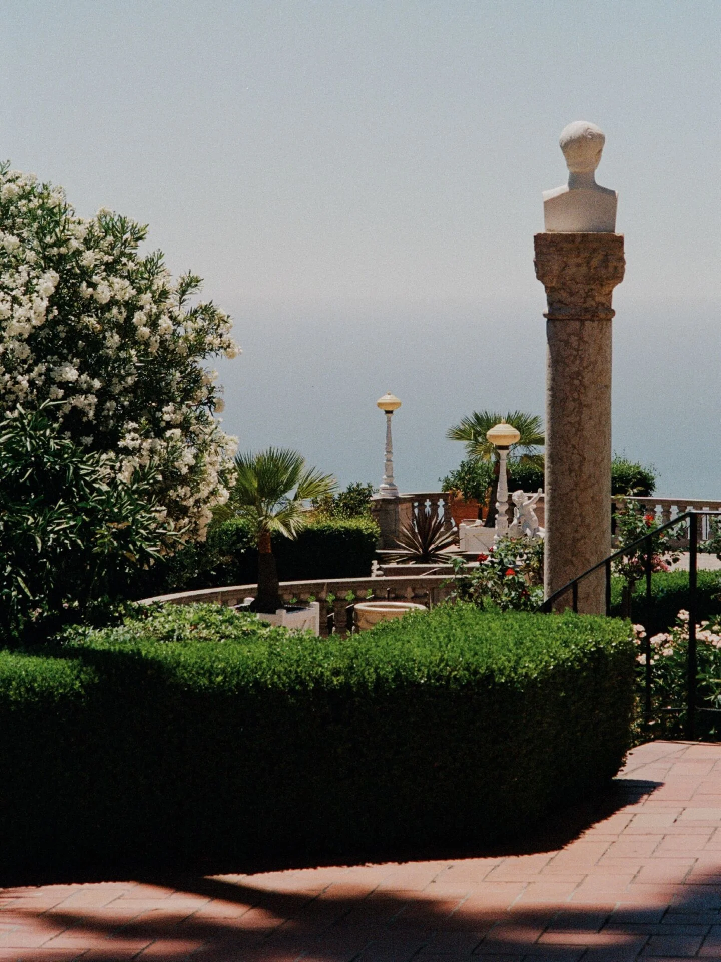 Terraço do Hearst Castle com busto sobre coluna e o Pacífico ao fundo