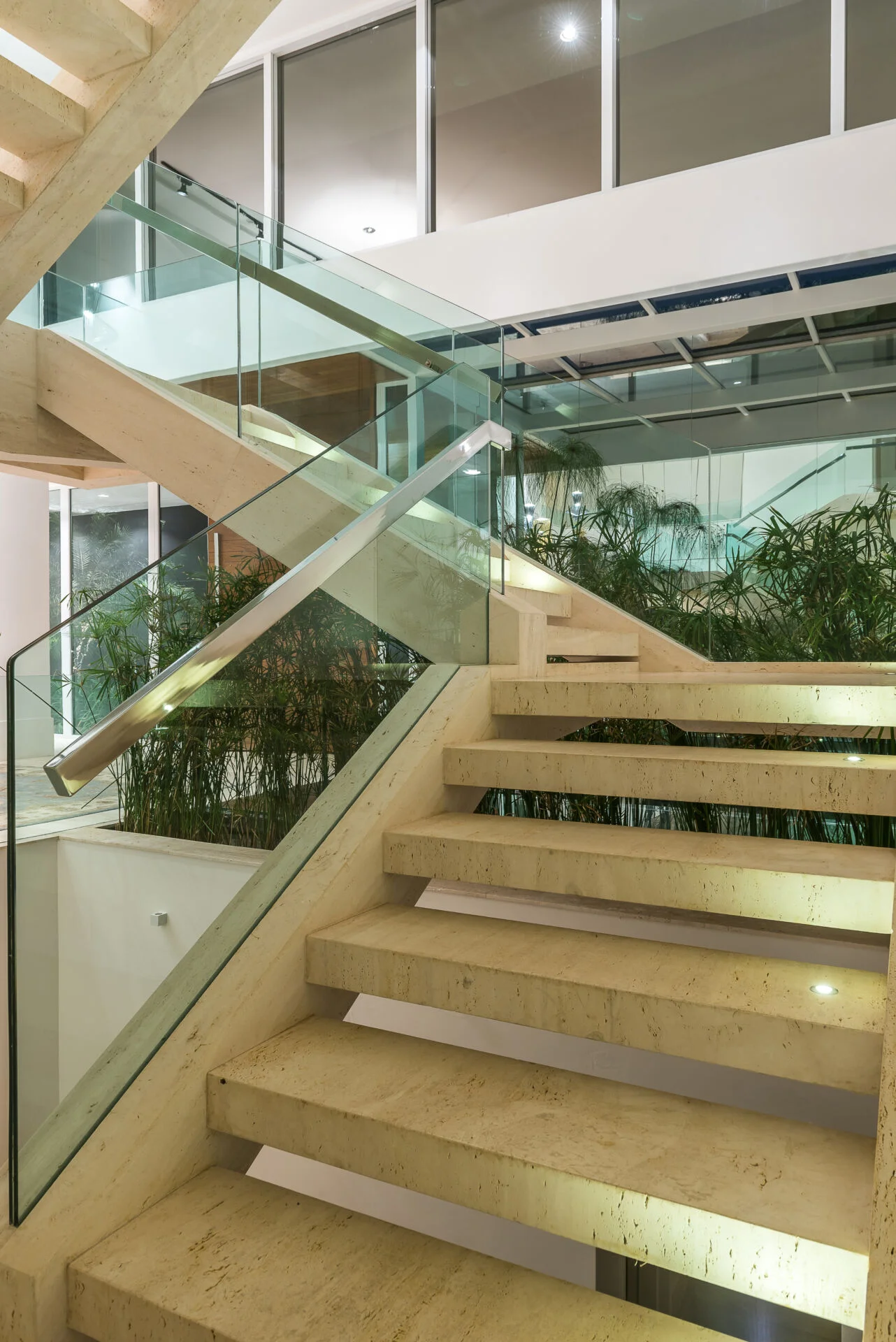Escada de vidro e pedra sobre jardim interno