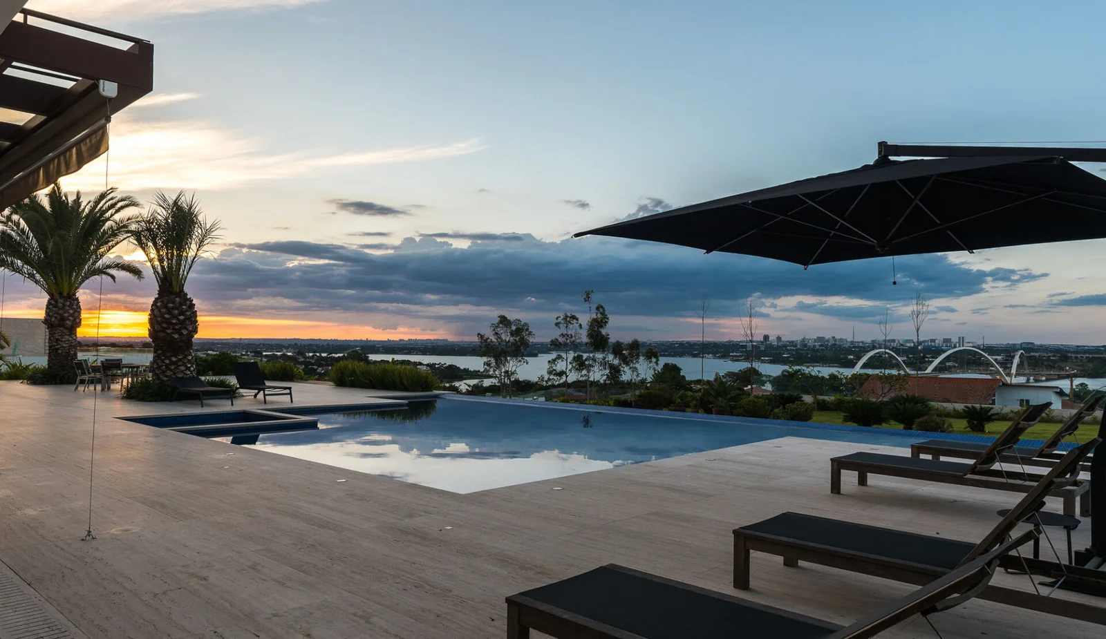 Piscina de borda infinita diante do Lago Paranoá ao entardecer