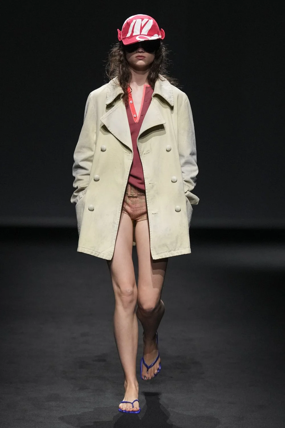 Look da MM6 Maison Margiela com trench claro e boné, calçando chinelos Havaianas