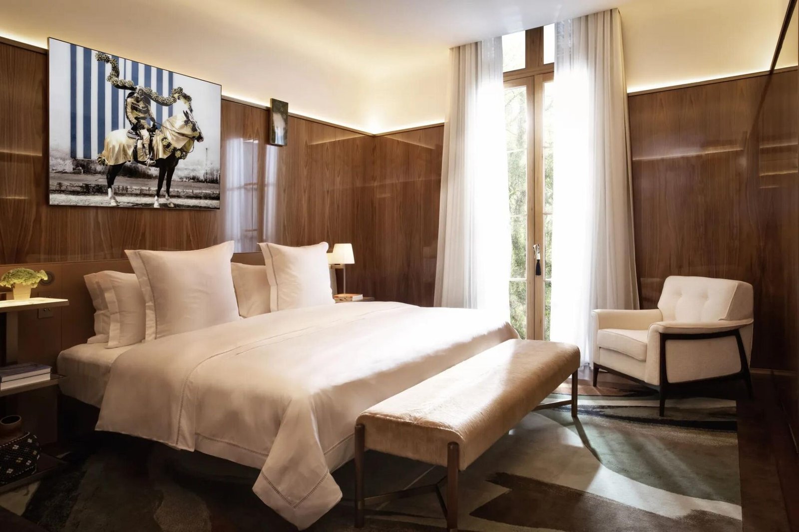Quarto da Matarazzo Suite com cama ampla, banco estofado aos pés e fotografia de um cavaleiro na parede