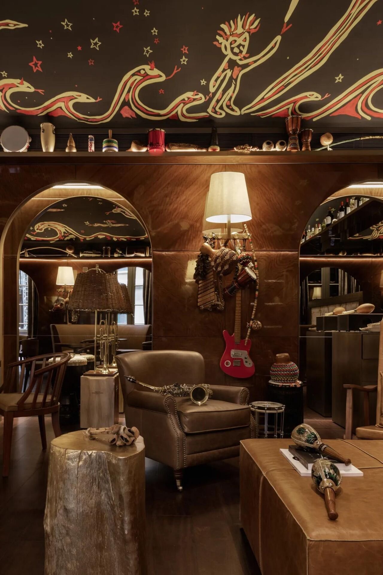 Interior do bar Rabo di Galo com arcos, teto pintado com ondas, luminária de palha e guitarra vermelha pendurada na parede de madeira