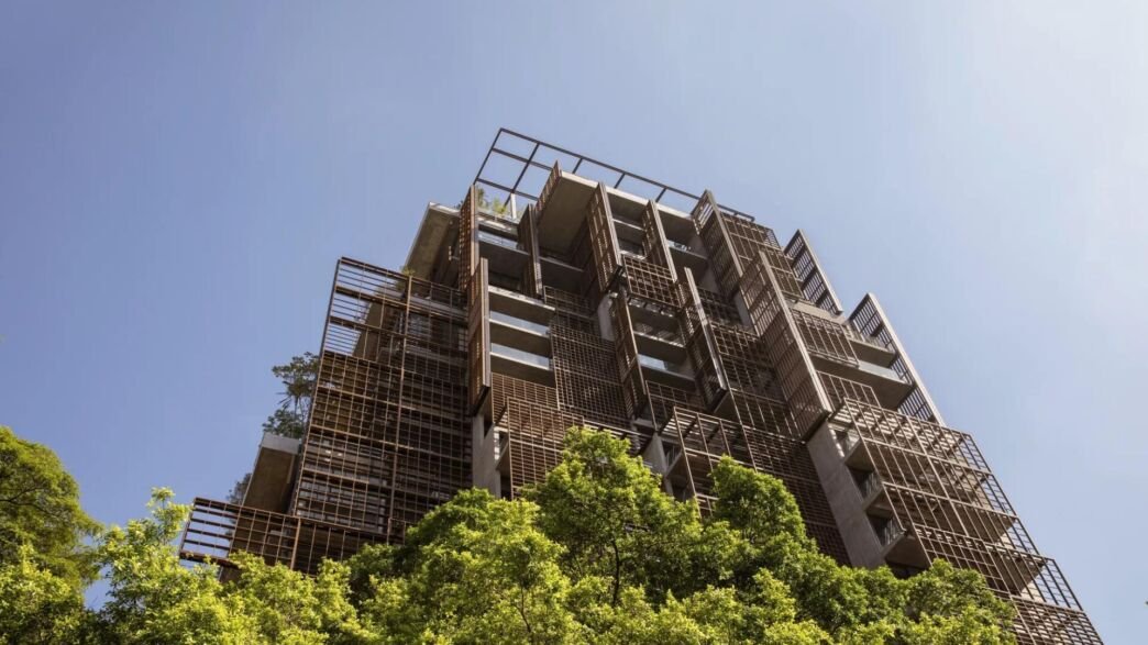 A Torre Mata Atlântica, de Jean Nouvel, vista de baixo, com as treliças de madeira da fachada acima das copas das árvores