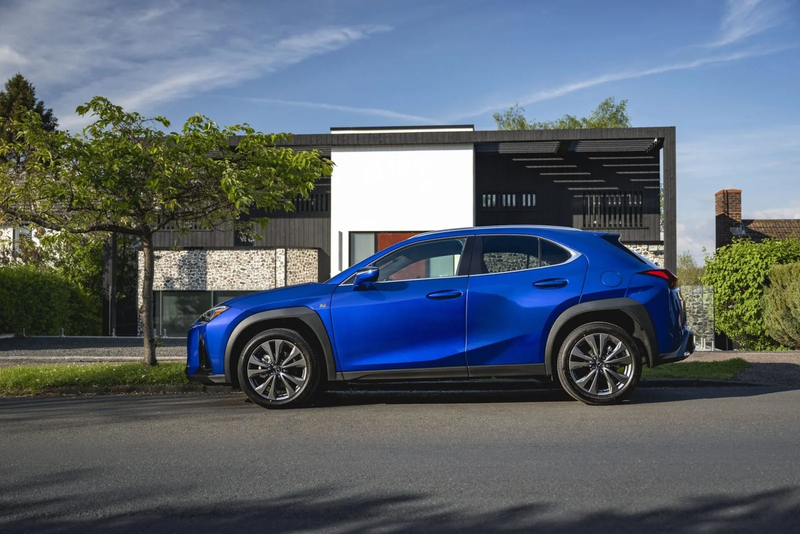 Perfil lateral do Lexus UX 300h azul mostrando a linha de teto baixa e as molduras escuras dos para-lamas.