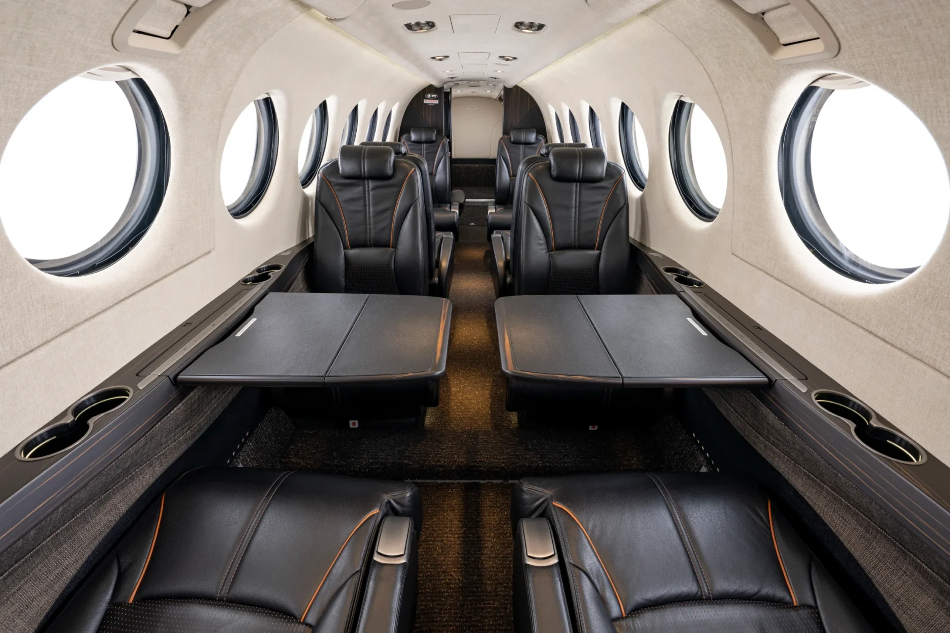 Cabine do King Air 360 em couro escuro, com poltronas em configuração club e janelas ovais