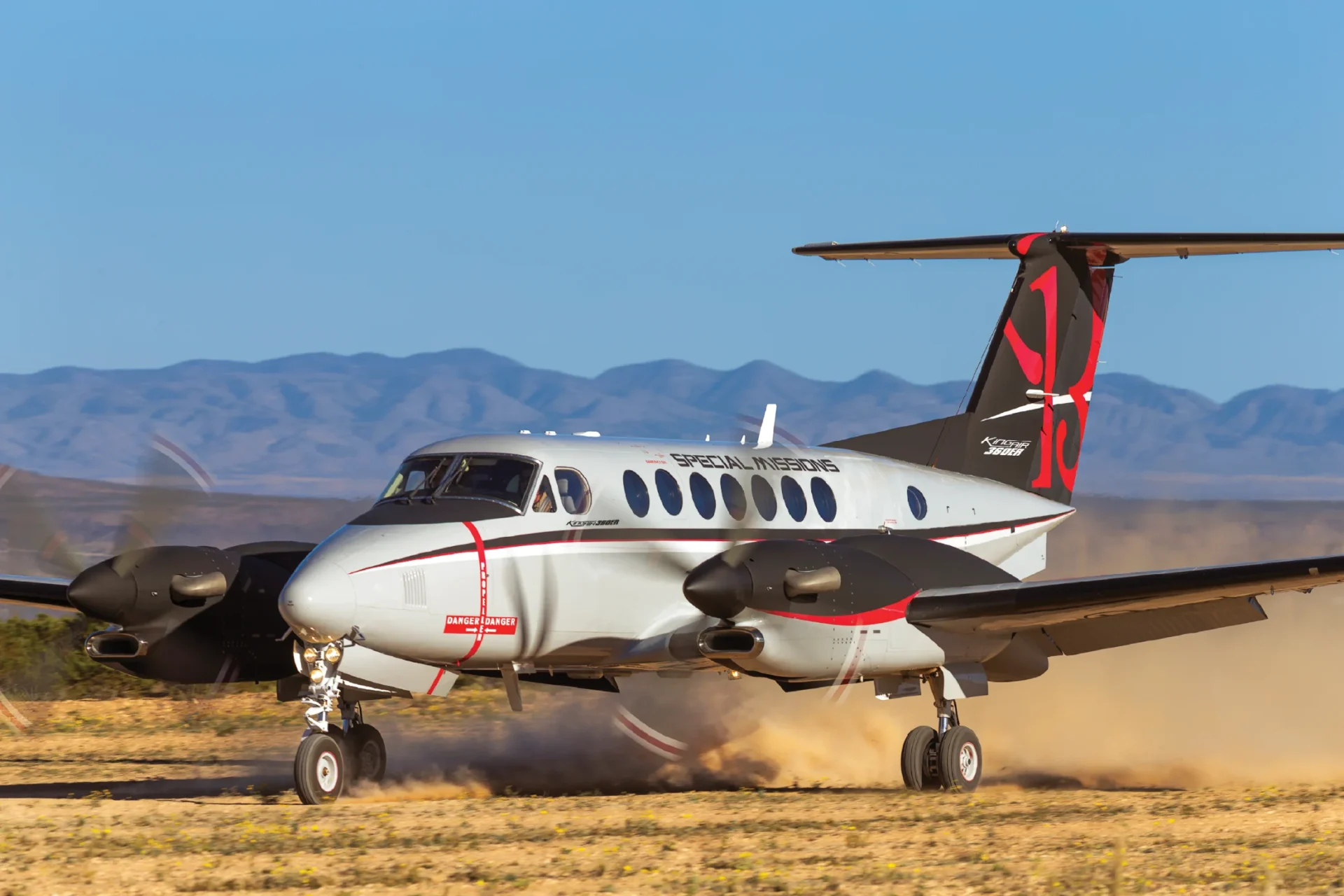 King Air 360ER decolando de pista de terra, com poeira levantada pelas hélices