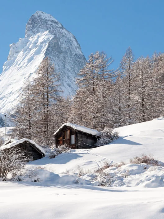 Chalés de Zermatt na neve com o Matterhorn ao fundo