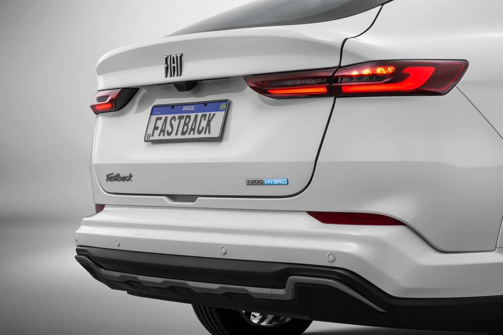 Detalhe da traseira do Fiat Fastback Impetus com lanternas de LED, placa Fastback e o emblema T200 Hybrid na tampa do porta-malas.