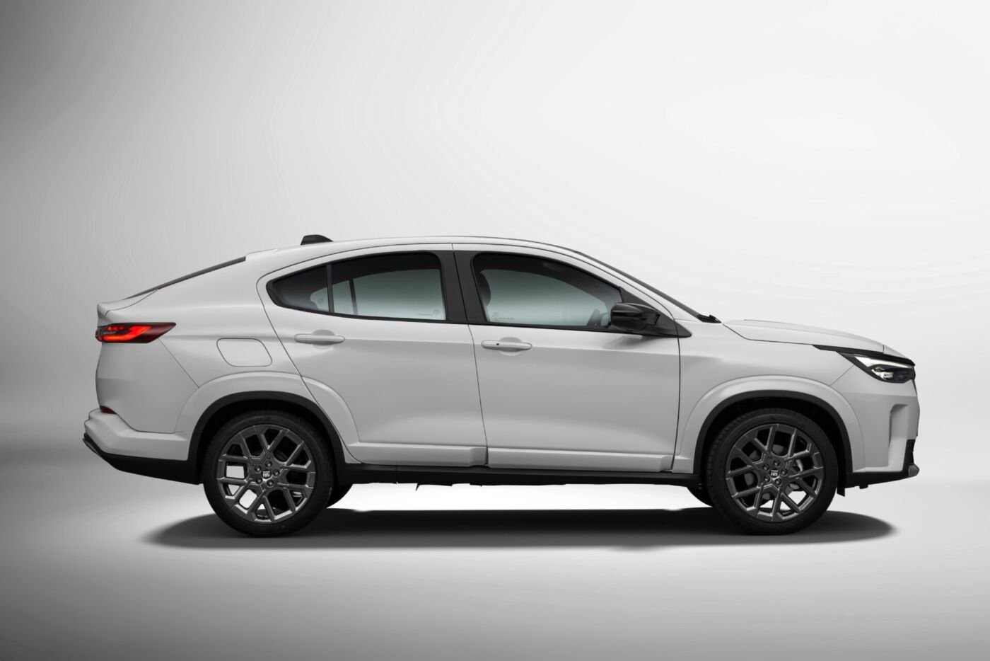 Perfil lateral do Fiat Fastback Impetus MHEV branco em estúdio, com a linha de teto descendo em curva contínua até a tampa do porta-malas e rodas de 18 polegadas escurecidas.