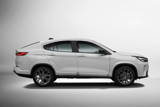Perfil lateral do Fiat Fastback Impetus MHEV branco em estúdio, com a linha de teto descendo em curva contínua até a tampa do porta-malas e rodas de 18 polegadas escurecidas.