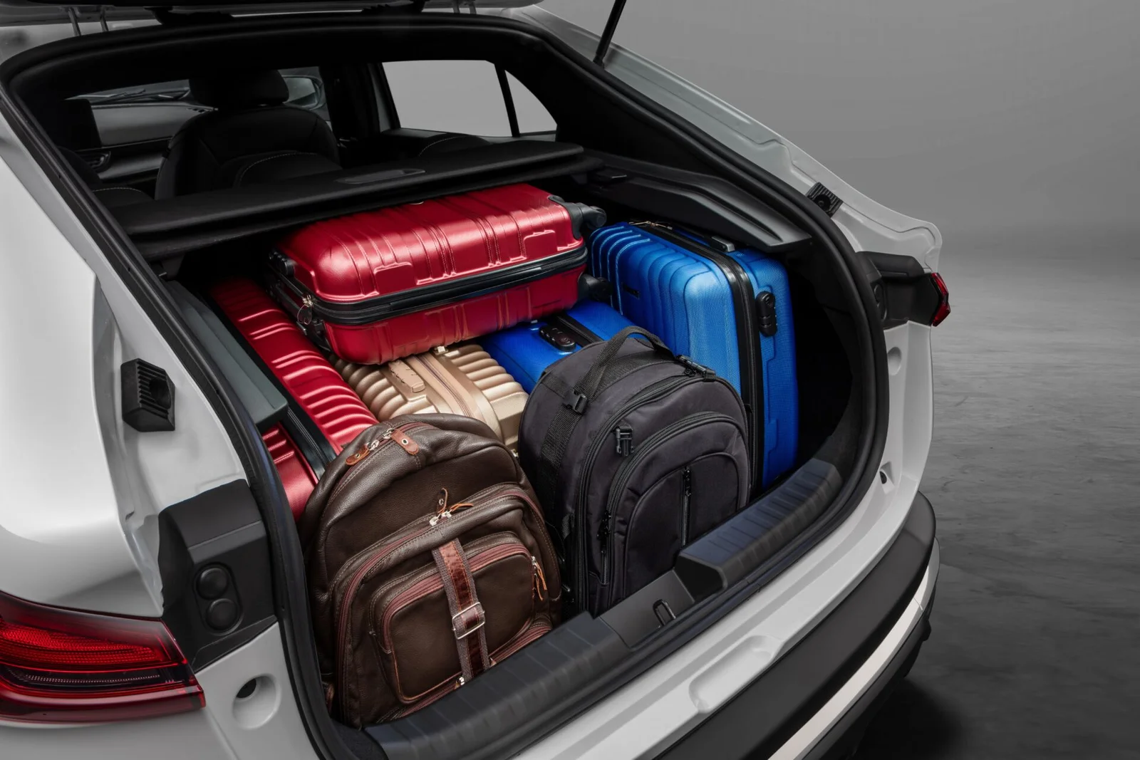 Porta-malas aberto do Fiat Fastback Impetus carregado com quatro malas rígidas e duas mochilas.