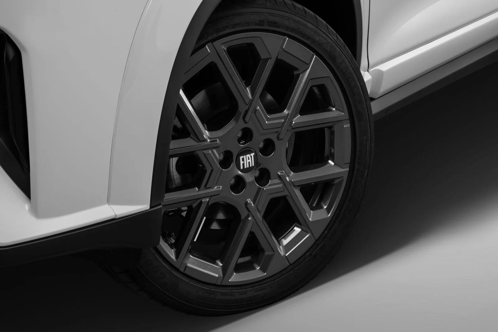 Roda de liga leve de 18 polegadas em grafite do Fiat Fastback Impetus, com raios em desenho geométrico e emblema Fiat no centro.