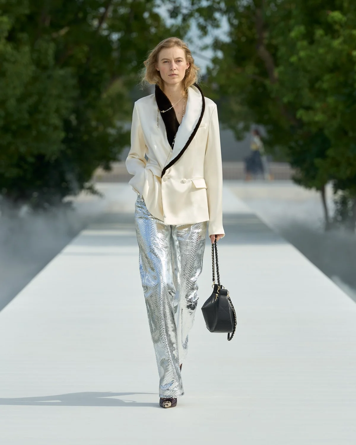 Look 5 de Dior Verão 2027, jaqueta marfim com gola xale preta e calça larga prateada
